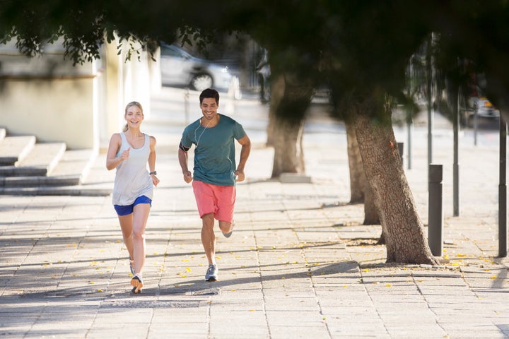 Couple running through city streets together Sam Edwards via Getty Images