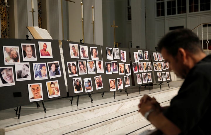 David Olson prays in front of photographs of victims of the shooting at the Pulse gay nightclub, during an Interfaith Service