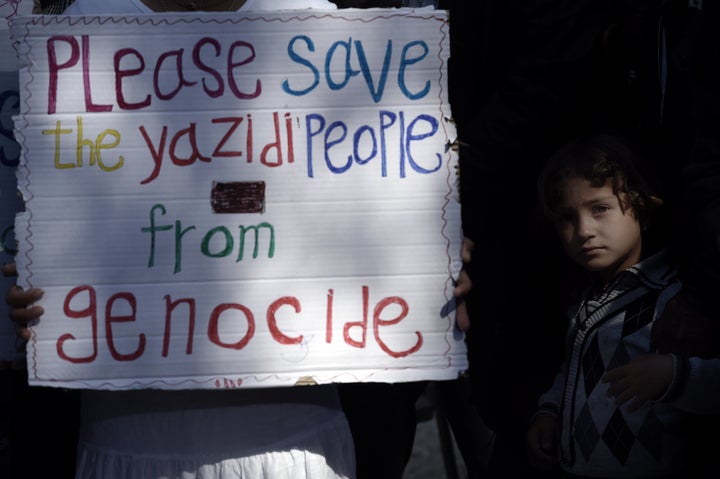 A migrant child stands next to a placard reading 'Please save the Yazidi people from genocide' at the Moria detention center during a visit of Pope Francis in Mytilene, on the Greek island of Lesbos in April.