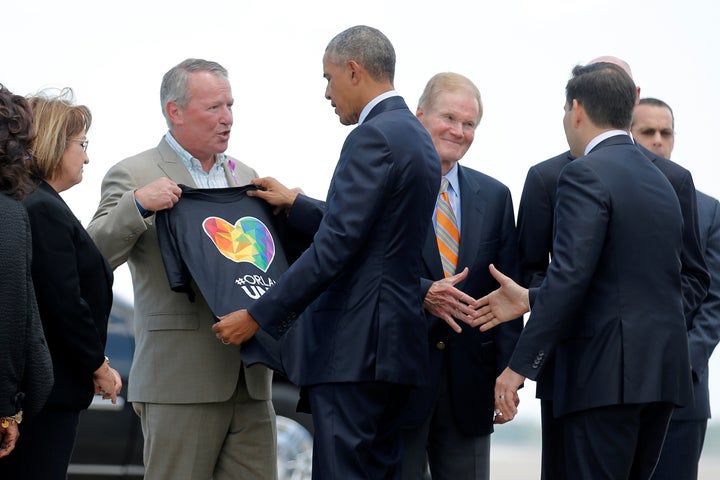 President Barack Obama receives a T-shirt from Orlando Mayor Buddy Dyer as he arrives in the city to meet with families
