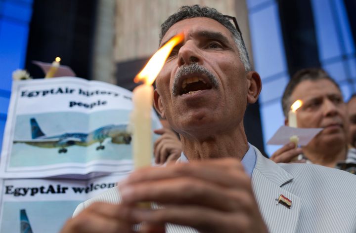 An Egyptian journalist holds a candle and a poster supporting EgyptAir during a candlelight vigil for the victims of EgyptAir flight 804