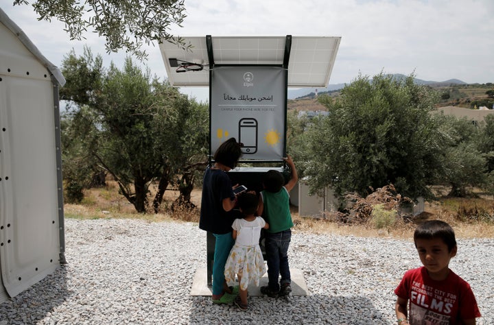 Children stand around a solar-powered charging station for mobile devices designed by a group of university students, at the municipality-run camp of Kara Tepe on the island of Lesbos, Greece, June 14, 2016.