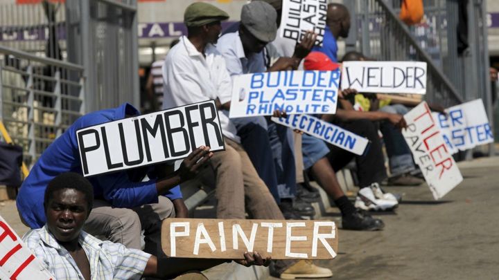 Men hold placards offering temporary services in Glenvista, near Johannesburg. Scenes like this inspired the creation of Giraffe, a mobile job recruitment site.