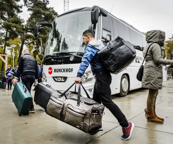 Refugees leave a shelter for refugees in Nijmegen, Netherlands, as they are being transferred to shelter locations and r