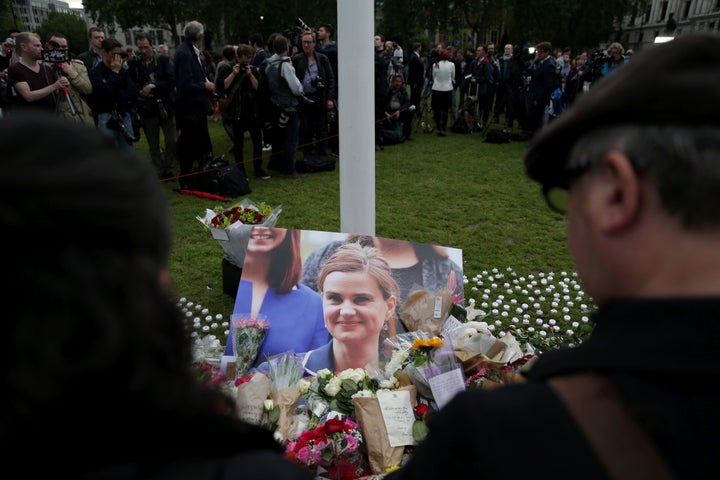 Members of the public gather at the heaped of tributes laid in remembrance of Jo in Parliament square