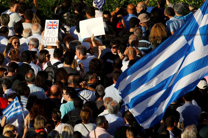 An anti-government demonstrator waves a Greek flag next to a placard that reads "No Brexit" outside the parliament during a protest in Athens, Greece