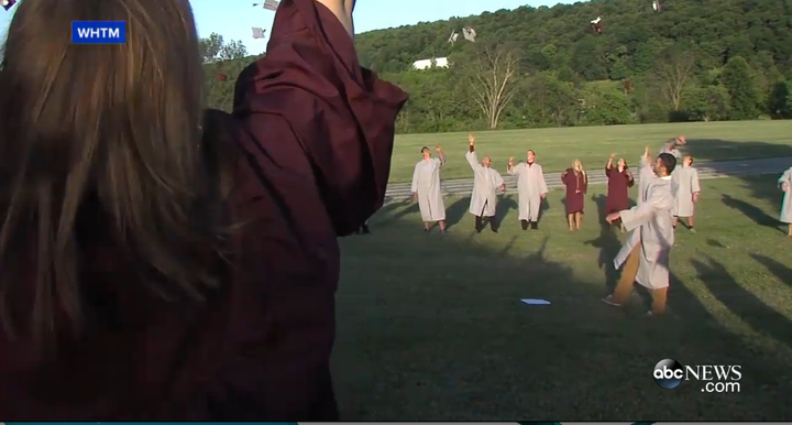 Students gather around Dunn to throw their caps into the air.