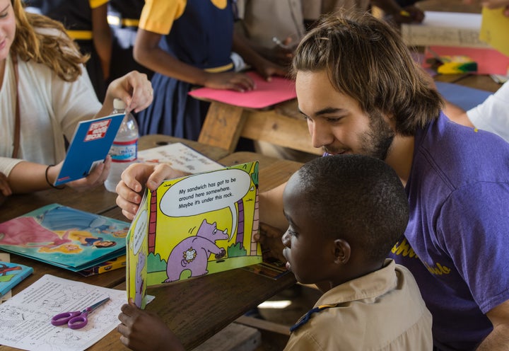 Millennial Jordan Kalkhurst reading with students in a school in Ocho Rios, Jamaica