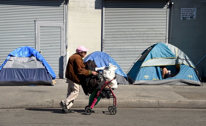 A woman pushes her walker past tents housing the homeless in Los Angeles, California.