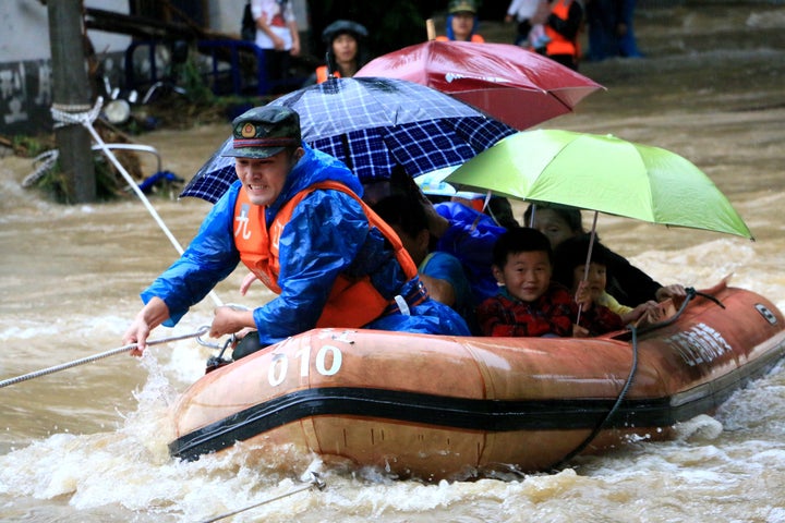 A rescuer grabs a rope to prevent a raft carrying residents from being flushed away as residents are evacuated from a flooded
