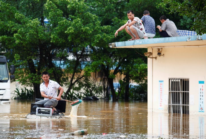 A man uses a foam board as a raft to transfer electronic devices away at a flooded building in Liuzhou, Guangxi Zhuang Autono