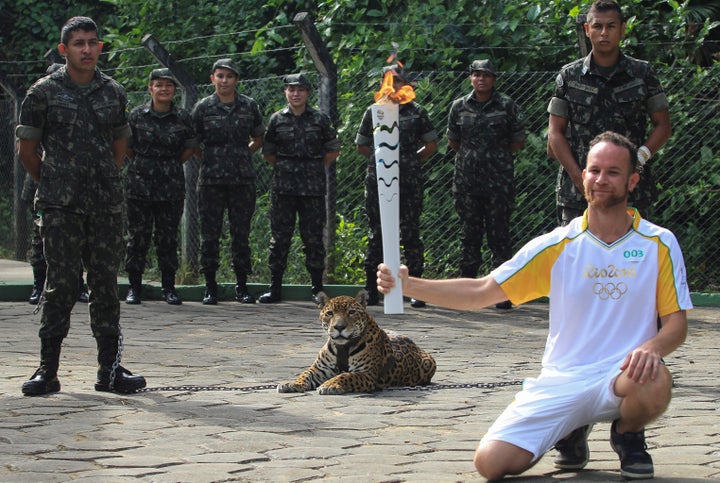 Brazilian physiotherapist Igor Simoes Andrade poses for picture next to jaguar Juma as he takes part in the Olympic Flame torch relay in Manaus, Brazil, June 20, 2016.