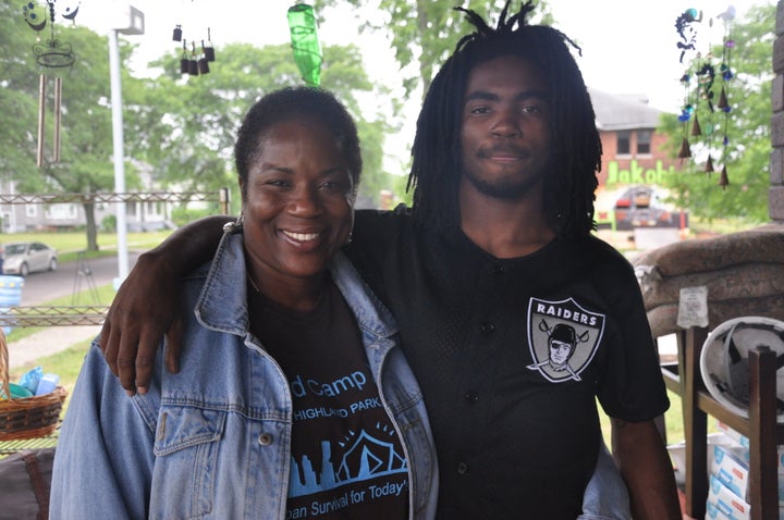 Chinyelu, 19, stands with his mom Shu Harris on the porch of their home on Avalon Street. A mural honoring Jakobi Ra, Chinyelu's younger brother who was killed by a hit-and-run driver in 2007, can be seen on the building in the background. It will become the Homework House.