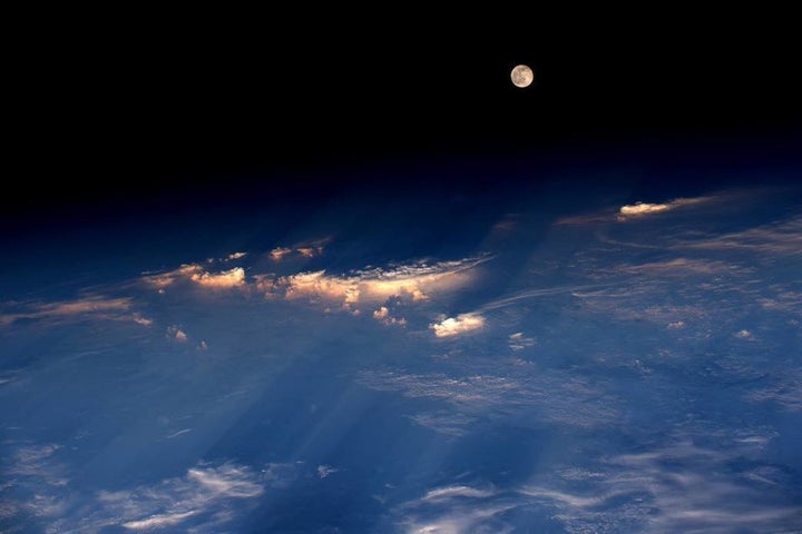 Astronaut Jeff Williams took this photograph of the rare Strawberry Moon emerging from the clouds while orbiting Earth from the International Space Station on Tuesday.