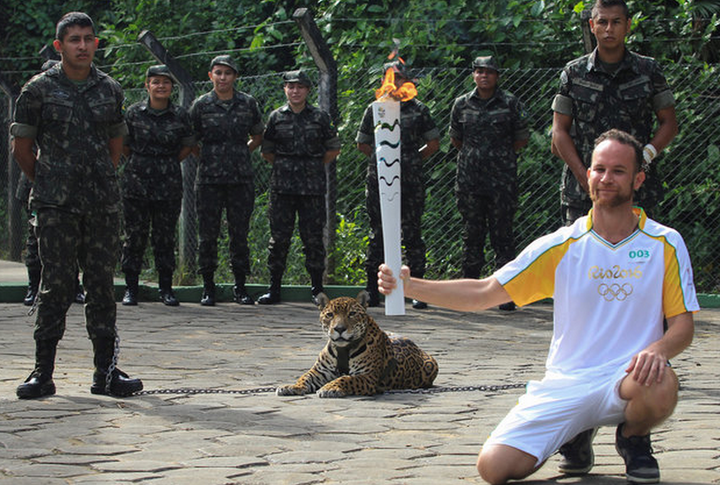 Brazilian physiotherapist Igor Simoes Andrade poses for picture next to Juma as he takes part in the Olympic Flame torch relay in Manaus, Brazil; the jaguar was later shot dead