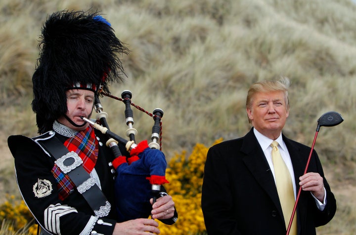 Donald Trump stands next to a bagpiper during a media event on the sand dunes of the Menie estate, the site for Trump's propo
