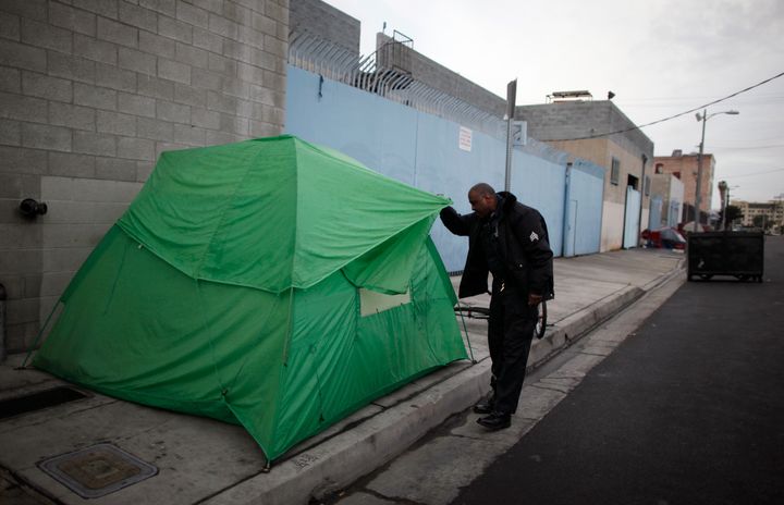 An LAPD sergeant looks to see if anyone is sleeping in a tent on downtown Los Angeles' Skid Row.