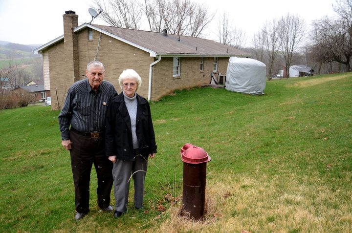 Jesse and Shirley Eakin stand by the water well they no longer use at their home in Avella, Pa. Delivered water is stored in the tank behind them.