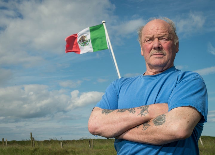 Michael Forbes poses for a photograph beside the Mexican flag he erected alongside Donald Trump's International Golf Links course, north of Aberdeen on the East coast of Scotland, on June 21, 2016.