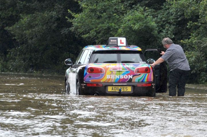 A driving instructor has to push his vehicle after he became stuck in the flooded road in Writtle, Essex