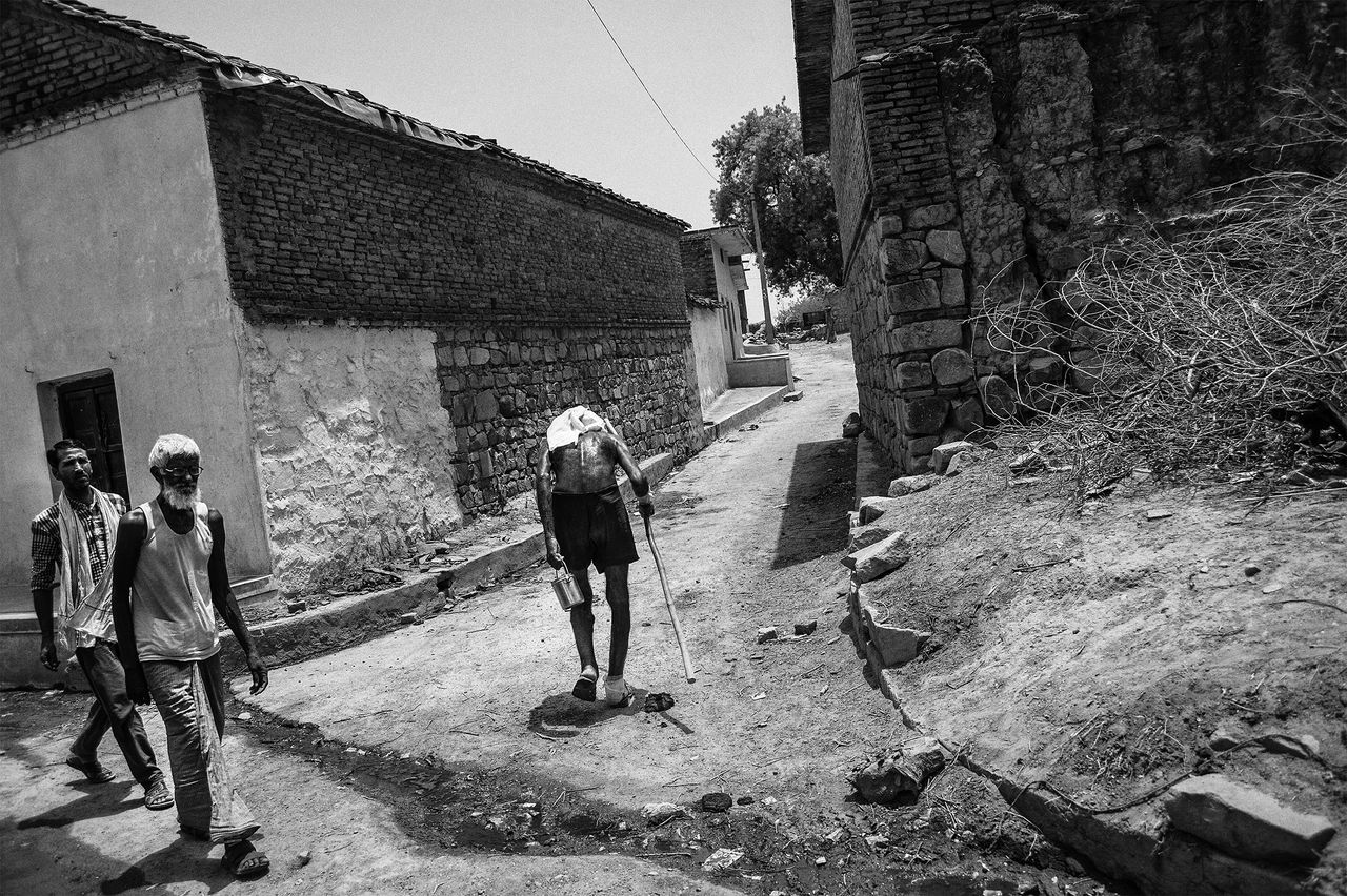 Weighed down by the burden of successive droughts, Narain Singh walks along a narrow village lane.