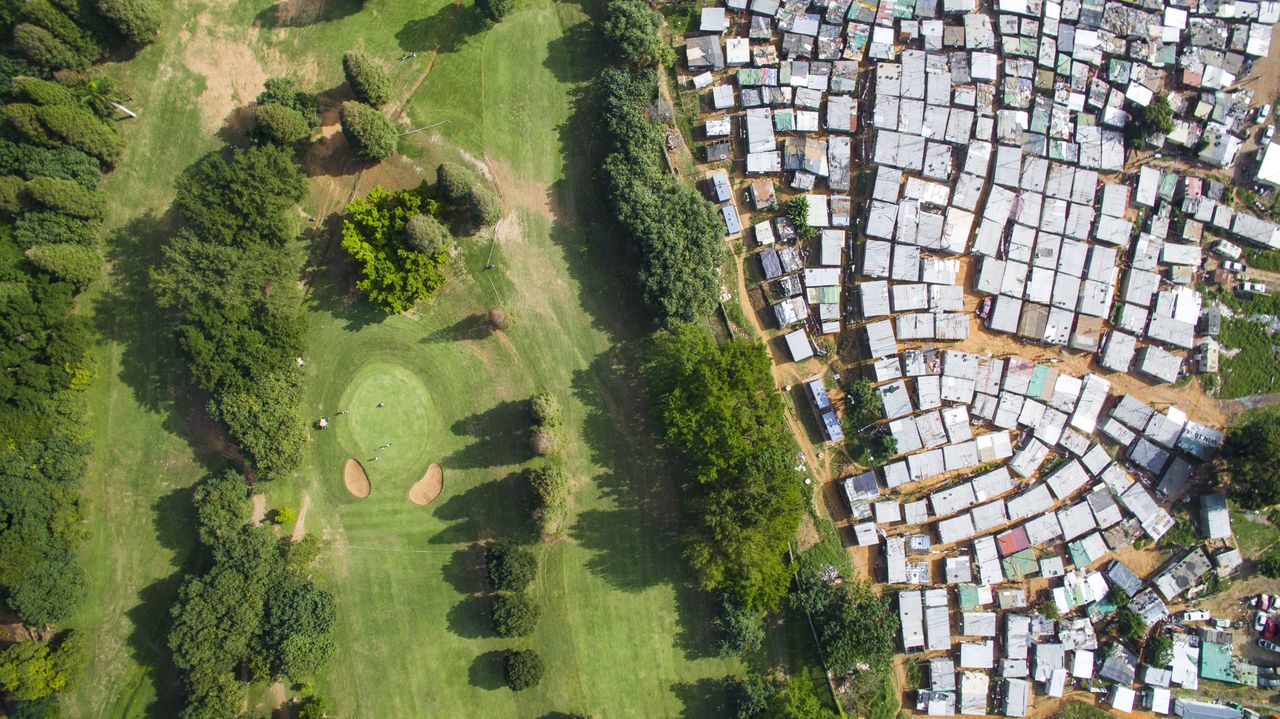 Papwa Sewgolum Golf Course is located along the lush green slopes of the Umgeni River in Durban. Almost unbelievably, a sprawling informal settlement exists just meters from the tee for Hole 6. A low-slung concrete fence separates the tin shacks from the carefully manicured fairways.