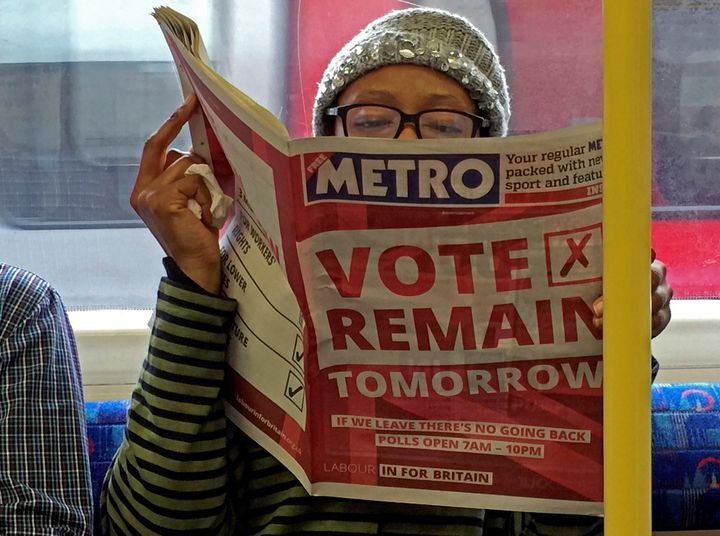 A woman reads a newspaper on the underground in London with a 'vote remain' advertisement for the Brexit referendum, June 2016.