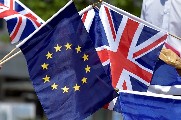 British students hold the UK Union and European Union flags in front of the European Parliament in Brussels.