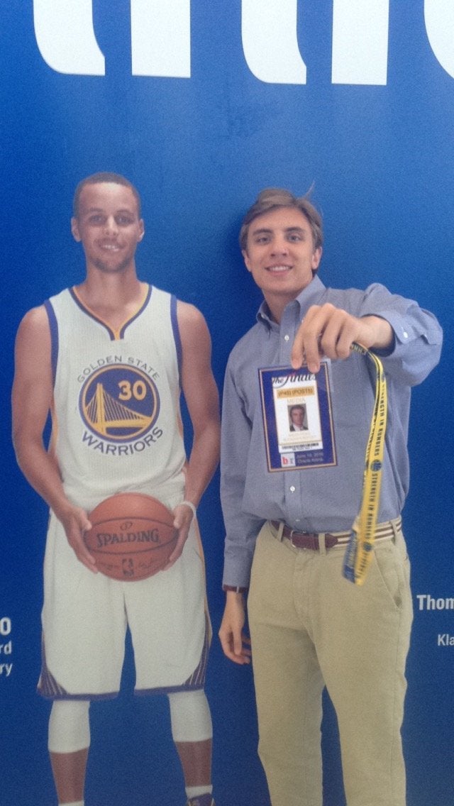 Micah Poag poses with his fake press pass and an image of Steph Curry.