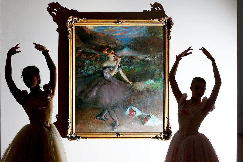 Ballerinas from The Australian Ballet are silhouetted as they pose next to one of Edgar Degas iconic ballet dancer paintings "Dancer with Bouquets."