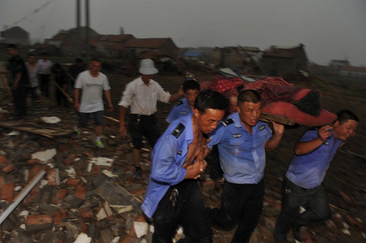 Rescue workers carry out an injured person from debris of damaged houses after a tornado hit Yancheng, Jiangsu province, Chin