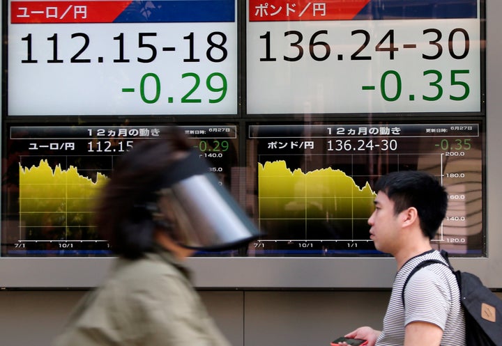 People walk by an electronic board displays exchange rate of euro, left, and British pound at the securities firm in Tokyo on Monday