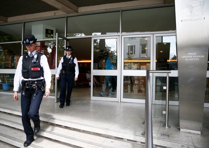 Police officers leave the Polish Social and Cultural Association after graffiti was painted on the side of the building.