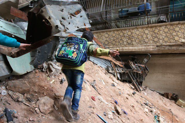A school-aged child navigates through rubble and barbed wire in Aleppo, Syria, Feb. 11, 2016.