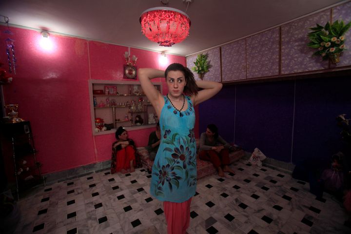 Transgender Maria fixes her hair as housemates speak in the background at their home in Peshawar, Pakistan June 27, 2016.