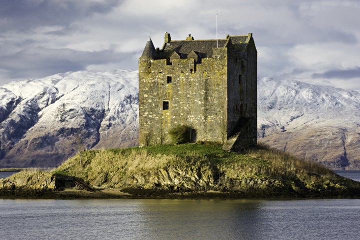 Scotland's Castle Stalker on Loch Linnhe, surrounded by snow covered mountains.