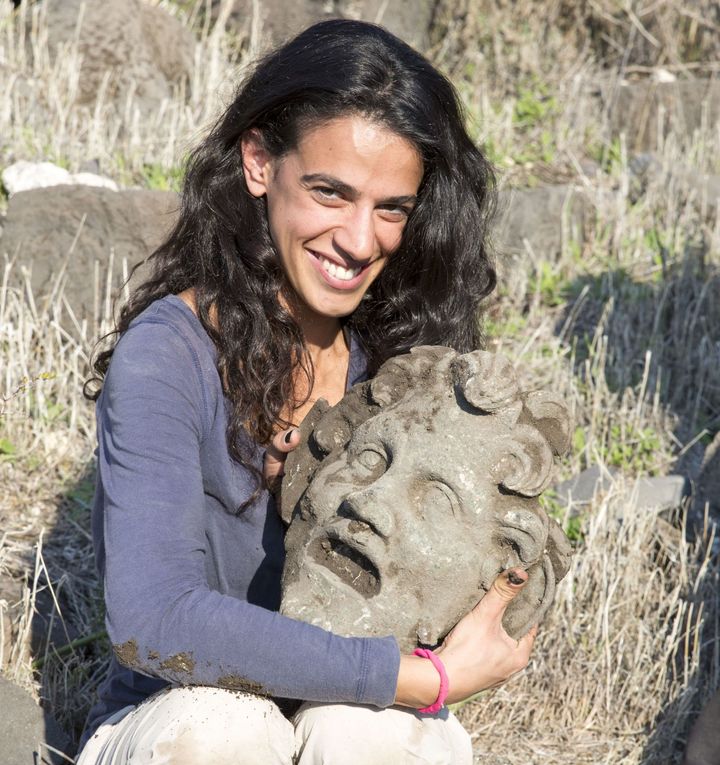A participant of the Hippos-Sussita excavation holds an ancient bronze mask believed to depict the pagan god Pan.