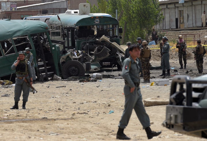 Afghan security personnel gather near the wreckage of buses which were carrying police cadets, at the site of a bomb attack o