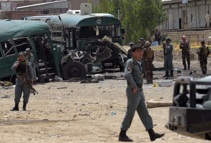 Afghan security personnel gather near the wreckage of buses which were carrying police cadets, at the site of a bomb attack on the outskirts of Kabul on June 30, 2016.