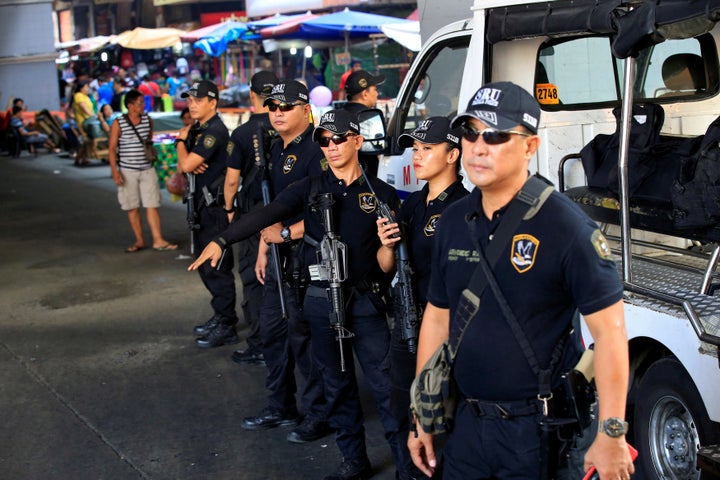 Members of the Philippine National Police Special Reaction Unit gather as part of a police visibility operation along a main road in Metro Manila.