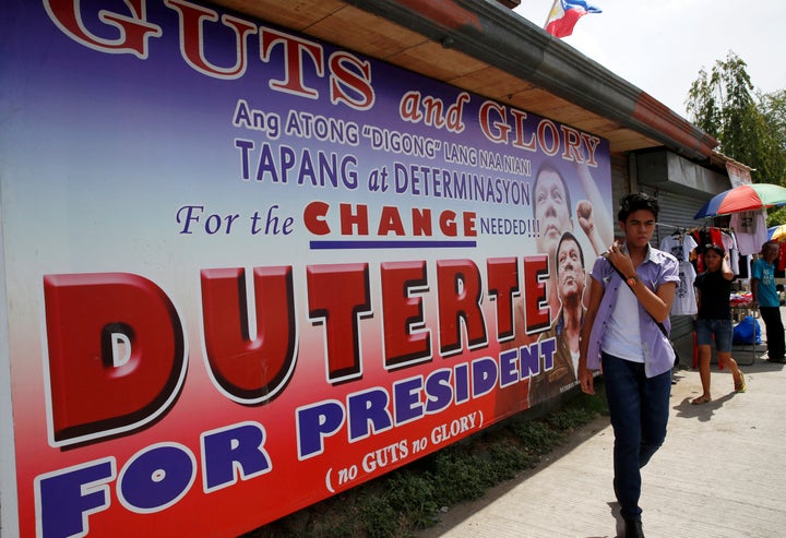 Residents walk past an election campaign poster of leading presidential candidate Rodrigo "Digong" Duterte in Davao city.