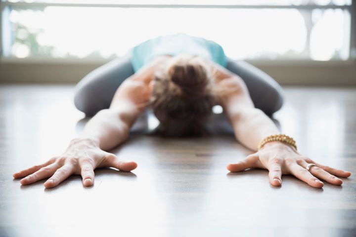 Woman practicing yoga in childs pose stretching arms Hero Images via Getty Images