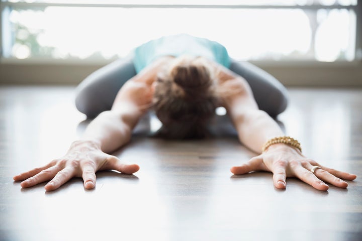 Woman practicing yoga in childs pose stretching arms Hero Images via Getty Images