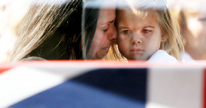 Emma-Jayne, the fiancee of Lance Corporal Richard Brandon of the Corps of Royal Electrical and Mechanical Engineers (REME) who was killed in Afghanistan, weeps with their daughter Kaitlin as his coffin passes them in Wootten Bassett, Wiltshire, in October 2009.