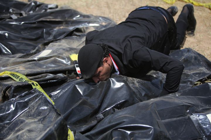 An Iraqi man kisses a body-bag lying amidst other bags containing the remains of people believed to have been slain by jihadists of the Islamic State (IS) group lie on the ground at the Speicher camp in the Iraqi city of Tikrit, on April 12, 2015. The Islamic State (IS) jihadist group executed hundreds of mostly Shiite recruits last June in what is known as the Speicher massacre, named for the military base near which they were captured. Thirteen grave sites have been found - 10 in the palace complex and three outside.