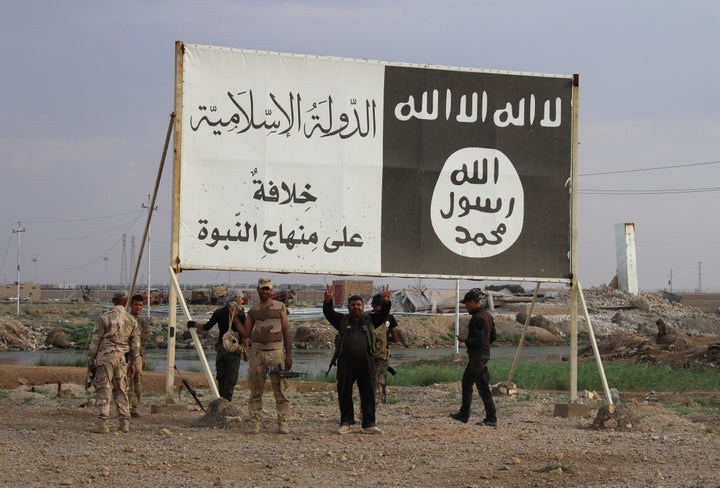 Iraqi government forces gather under a billboard bearing slogans of the Islamic State group in Iraq's Anbar province on