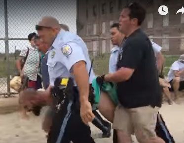 Fox is carried by police officers off the beach and placed under arrest