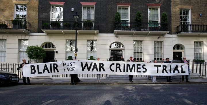 Protesters hold a banner outside the London home of former Prime Minister Tony Blair