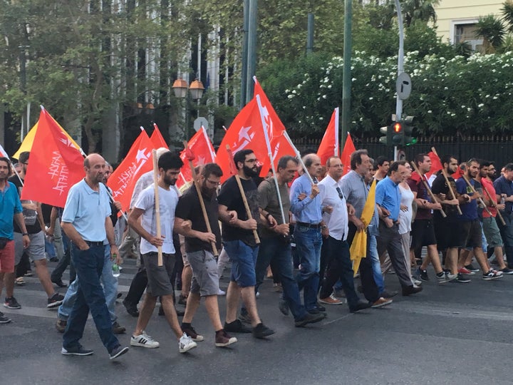 Greek protesters march against austerity, holding the flags of socialist factions.