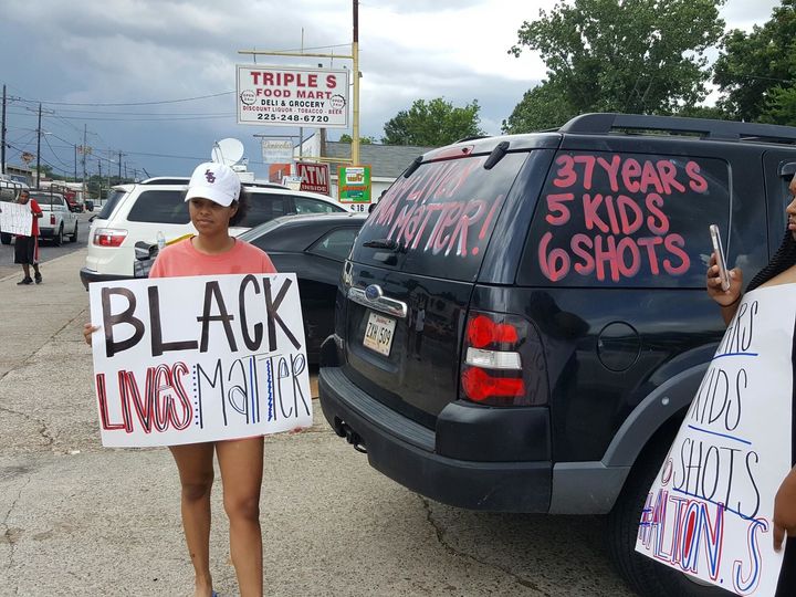 A woman outside the Triple S convenience store holds a sign in support of Sterling.
